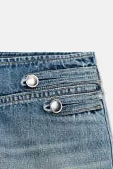 Shorts mini de denim de tiro bajo con diseño de costuras decorativas y botones metálicos en la parte frontal.