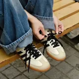 Championes Adidas Samba Og color beige con detalles en negro y suela de goma marrón.