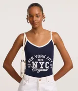Body de tirantes finos color azul marino con ribete blanco en escote y tirantes. Presenta un estampado grande en blanco con el texto "NEW YORK CITY 1978 NYC Original".