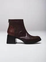 Botinetas de cuero vacuno con textura tipo reptil en color marrón chocolate. Presentan un diseño de caña media con cierre posterior, puntera redondeada y suela de goma con taco cuadrado robusto.