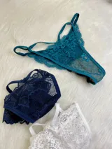 Pack de tres bombachas tipo tanga con diseño de encaje y tiras ajustables. El set incluye modelos en colores bordó, negro y blanco, confeccionados con detalles de encaje floral y terminaciones delicadas.