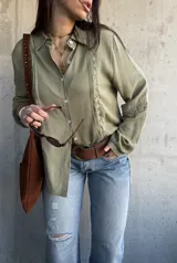 Camisa de manga larga color verde militar con inserciones de encaje decorativo en el frente y las mangas, cuello camisero y cierre frontal de botones.