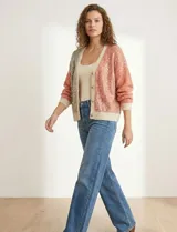 Cardigan de punto con escote en V y abotonadura frontal. Presenta un diseño colorblock con paneles en beige claro, rosa salmón y beige con lentejuelas dispersas. Las mangas son largas y abullonadas con puños y ruedo en punto acanalado beige claro.