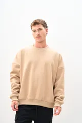 Buzo color beige de corte holgado, con cuello redondo y mangas largas.