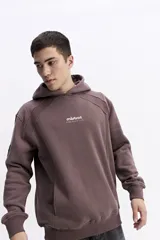 Canguro de felpa color crema, con capucha y bolsillo canguro frontal. Presenta un pequeño estampado con el logo de la marca en el pecho.