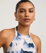 Vestido largo estilo slip con cuello halter que se ata en la nuca, sin mangas, con estampado abstracto en tonos azul y blanco que simula un efecto tie-dye.