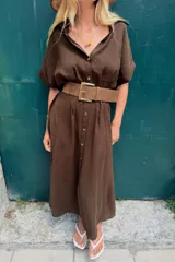 Vestido midi marrón con cuello solapa, escote en pico, mangas cortas con vuelta y cierre frontal con botones. Incluye un cinturón ancho a juego con hebilla metálica rectangular.
