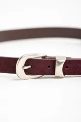 Cinto de cuero negro con textura de gamuza, presenta una hebilla metálica plateada de diseño clásico y puntera metálica a juego.