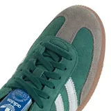 Championes Adidas Samba OG, color verde bosque con puntera de gamuza gris y tres franjas laterales blancas. Suela de goma color caramelo.