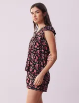 Conjunto de pijama de short y remera en tejido soft estampado. Remera de escote en V con aplique de puntilla, botones y detalle plisado. Short con cintura elastizada.