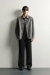 Sobrecamisa gris de corte regular fit con textura, cuello solapa, cierre frontal de botones, bolsillos de parche en el pecho y los laterales, y mangas largas con puños abotonados.