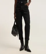 Pantalón de jeans estilo mom, tiro alto, color celeste claro lavado. Presenta bolsillos delanteros tipo carpinteiro con costuras marcadas y puños doblados en el bajo.