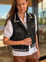 Chaleco de jean negro con apliques de caracoles cosidos a mano en los bordes.