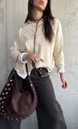 Sweater de punto color beige con bordado floral en el pecho, mangas largas y cuello redondo.