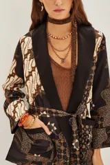 Saco tipo kimono con estampado batik en tonos marrones y negros, con solapas lisas, mangas largas y lazo ajustable en la cintura. Incluye bolsillos frontales y forro interior.