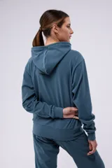Hoodie azul con capucha y cordón blanco y verde. Tiene un pequeño logo estampado en el pecho y un parche con el logo de la marca en el lateral.