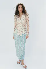 Camisa de cuello solapa y manga larga, con estampado de flores y cierre frontal cruzado.