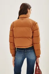 Campera puffer color tostado, con cierre frontal y botones a presión, cuello alto y puños tejidos acanalados.