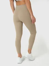 Conjunto deportivo de dos piezas compuesto por un top deportivo de escote redondo y calzas largas de tiro alto, ambos en color beige. El set destaca por su diseño minimalista y ajuste cómodo.