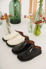 Zuecos color blanco con punta cuadrada y suela negra.