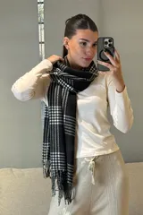 Bufanda rectangular de tejido suave con diseño de patrón escocés en tonos rosado y blanco, terminada con flecos en los extremos.