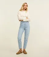 Pantalón de jean estilo mom, de tiro alto, con cierre de cremallera y botón, bolsillos frontales y traseros, y bajo con dobladillo.
