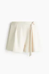 Short de tiro alto color beige en punto pesado con pinzas de estilo sastrero, elástico oculto en la parte posterior y cinturón incorporado con anillas metálicas en D en el lateral.