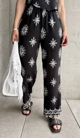 Pantalón negro con estampado de rombos blancos, de corte recto y tiro alto.