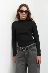 Polera negra de cuello alto y manga larga, confeccionada en tejido de punto acanalado.