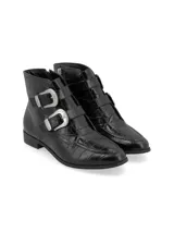 Botín de cuero vacuno con textura efecto croco, color negro. Presenta un diseño de caña baja con dos correas ajustables sobre el empeine, decoradas con hebillas metálicas plateadas de estilo western. Cuenta con taco bajo cuadrado y cierre lateral interno.