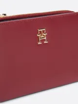 Billetera de diseño plegable y fino, color bordó, con sutil acabado granulado, cierre de botón a presión e insignia del monograma TH en la parte delantera.