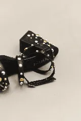 Sandalias de tacón ancho de 7 cm, color bordó, con diseño de tiras cruzadas en el empeine y pulsera al tobillo con cierre de hebilla. El modelo está decorado con tachas metálicas plateadas y doradas distribuidas por todas las tiras y el tacón.