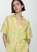 Camisa de manga corta con estampado floral en tonos verde y amarillo. Diseño oversize con cuello camisero y cierre frontal con botones.