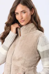 Chaleco de sherpa con cierre frontal, cuello alto y bolsillos laterales. Presenta detalles en cuero sintético en los tiradores de los cierres.