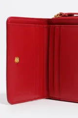 Billetera compacta de piel vacuna negra con estructura rígida, cierre de cremallera perimetral y tirador de tela en color turquesa. Incluye logo metálico dorado en el frente.