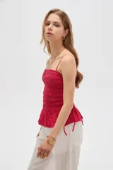 Top de algodón con diseño estampado de cuadros vichy en tonos celeste y blanco, corte al cuerpo con escote recto y tirantes finos. Presenta cuerpo fruncido tipo smock con cordones ajustables en los laterales que forman un pequeño volado en el ruedo.