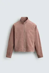 Cazadora de corte cropped confeccionada en piel con acabado serraje. Presenta cuello subido, cierre frontal de cremallera, manga larga con puños abotonados y bolsillos laterales de vivo.