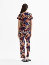 Babucha de algodón con estampado floral y de serpientes en tonos naranja, azul y verde sobre fondo azul marino. Tiene cintura elastizada con cordón ajustable y calce regular.