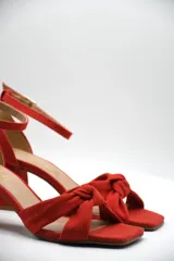 Sandalia de tacón medio ancho con diseño de nudo frontal y pulsera ajustable al tobillo con hebilla metálica.