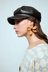 Aros de acrílico en forma de flor color beige con centro negro.