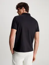 Chomba Calvin Klein negra de algodón, con cuello polo y media cremallera. Tiene mangas cortas y parche de goma con el logo de la marca en el pecho.
