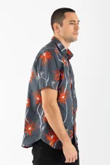 Camisa de manga corta con estampado de palmeras en tonos naranja y blanco sobre fondo gris.