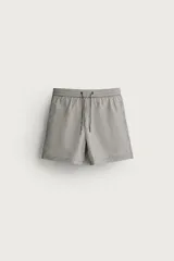 Short de baño de hombre confeccionado en tejido técnico con textura seersucker a rayas verticales en tono verde militar y blanco, con cintura elástica ajustable con cordón y bolsillos laterales.