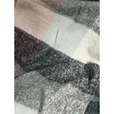 Bufanda rectangular de tejido grueso con diseño de cuadros en tonos azul, naranja, gris y beige, terminada con flecos en los extremos.
