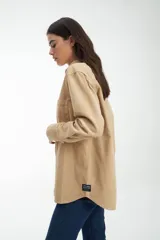 Camisa marrón de pana con cuello clásico, cierre con botones y dos bolsillos frontales con solapa.