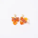Caravanas con diseño de flor en resina traslúcida color ámbar, con gancho metálico dorado.