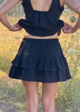 Falda corta color marrón con diseño de volados escalonados y short interior incorporado. Presenta una textura sutilmente rayada y una silueta liviana y fluida.