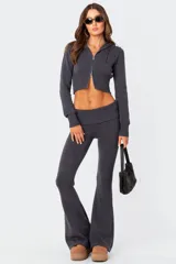 Conjunto de dos piezas de tejido de punto color gris oscuro, compuesto por un buzo tipo hoodie corto con cierre frontal y un pantalón de tiro bajo con corte acampanado.