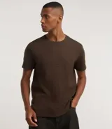 Remera de manga corta y cuello redondo, color marrón oscuro, confeccionada en tejido waffle de algodón.