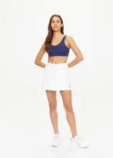 Short pollera blanco de algodón orgánico tejido con cintura con cordón y logo TU bordado en dorado en la parte delantera.